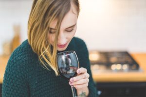 Woman looking down while holding a glass of red wine.