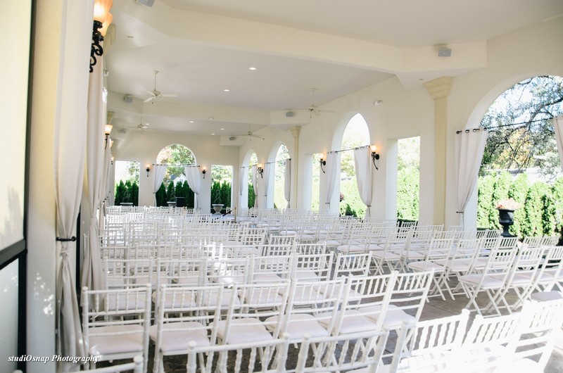 Outside wedding ceremony space with white chairs set up.
