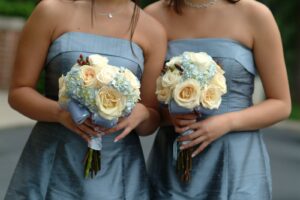 Bridesmaids in slate blue dresses holding flowers.