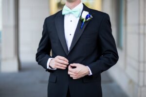 Zoom in of grooms suit and baby blue bowtie. 