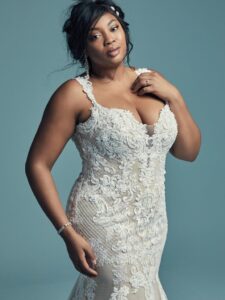 This elegant fit-and-flare wedding dress offers additional coverage. Featuring embroidered lace motifs and crosshatching dance over tulle. Chic lace straps glide from the illusion plunging sweetheart neckline to the scoop back, all accented in beaded lace motifs. Lined with shapewear for a figure-flattering fit. Finished with covered buttons over zipper closure.
