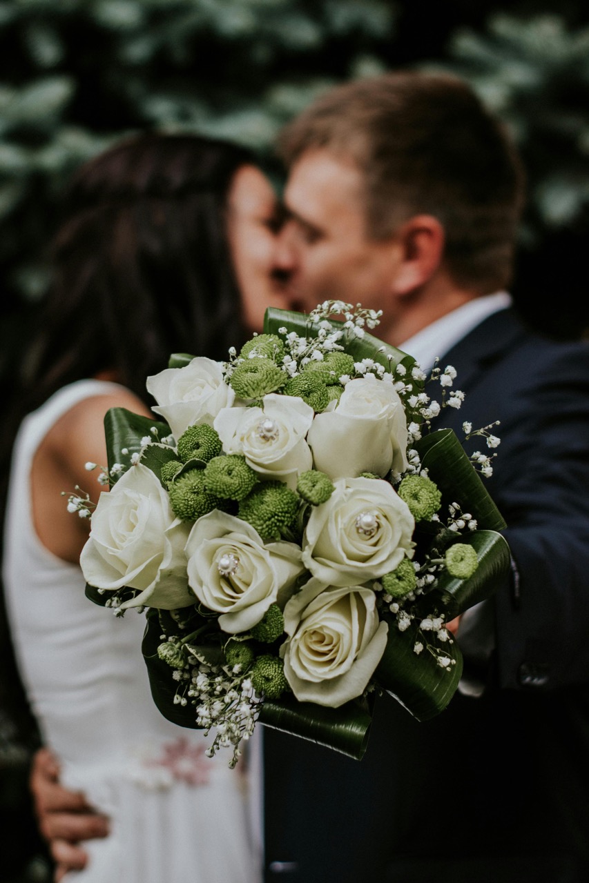 bride and groom kissing with bouquet of flowers