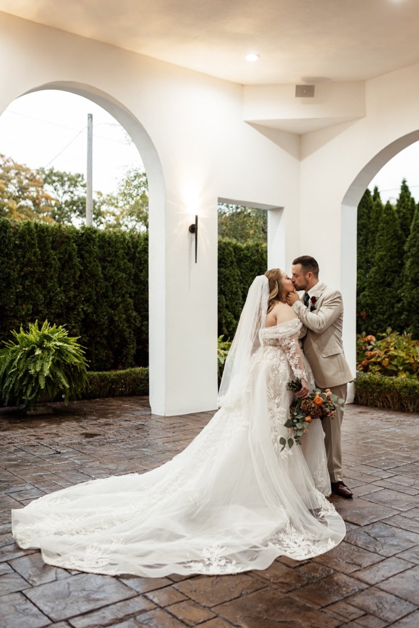 Bride and groom kissing outside in open-air chapel