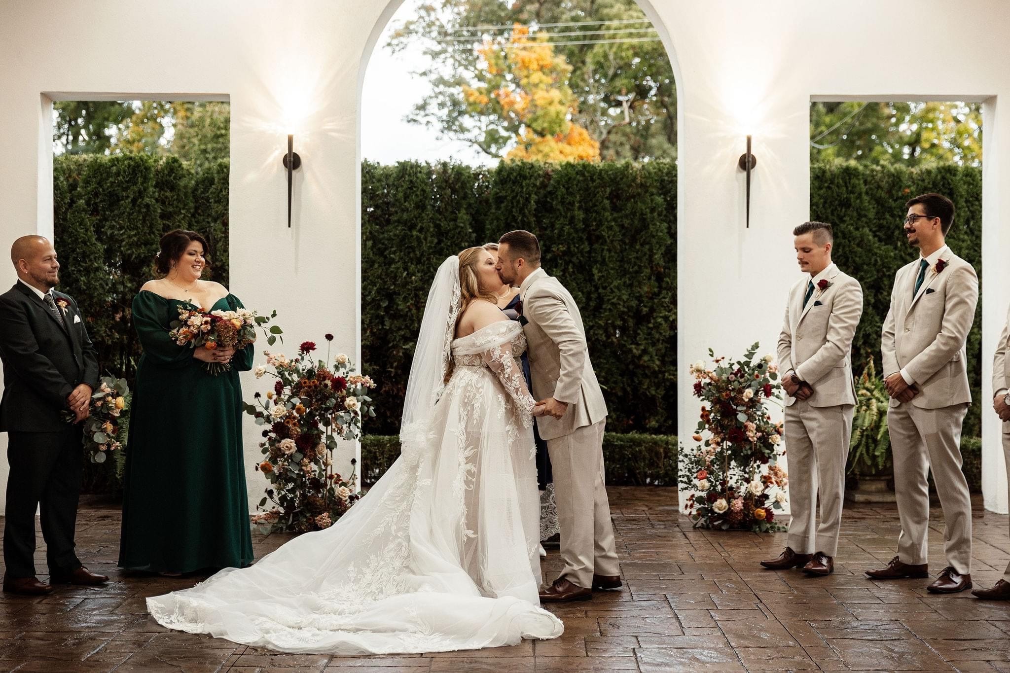 bride and groom kissing with wedding party standing next to them