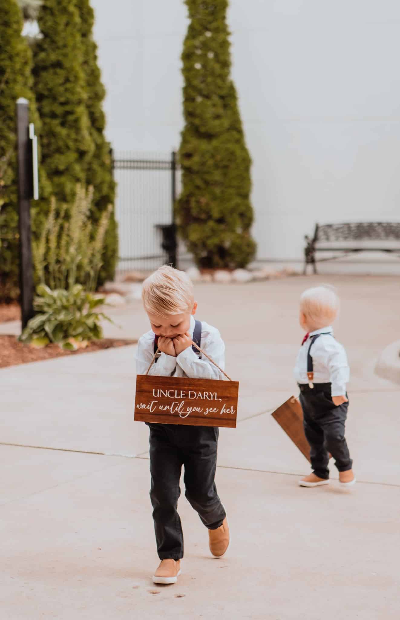 two little boys in tuxes carrying sign