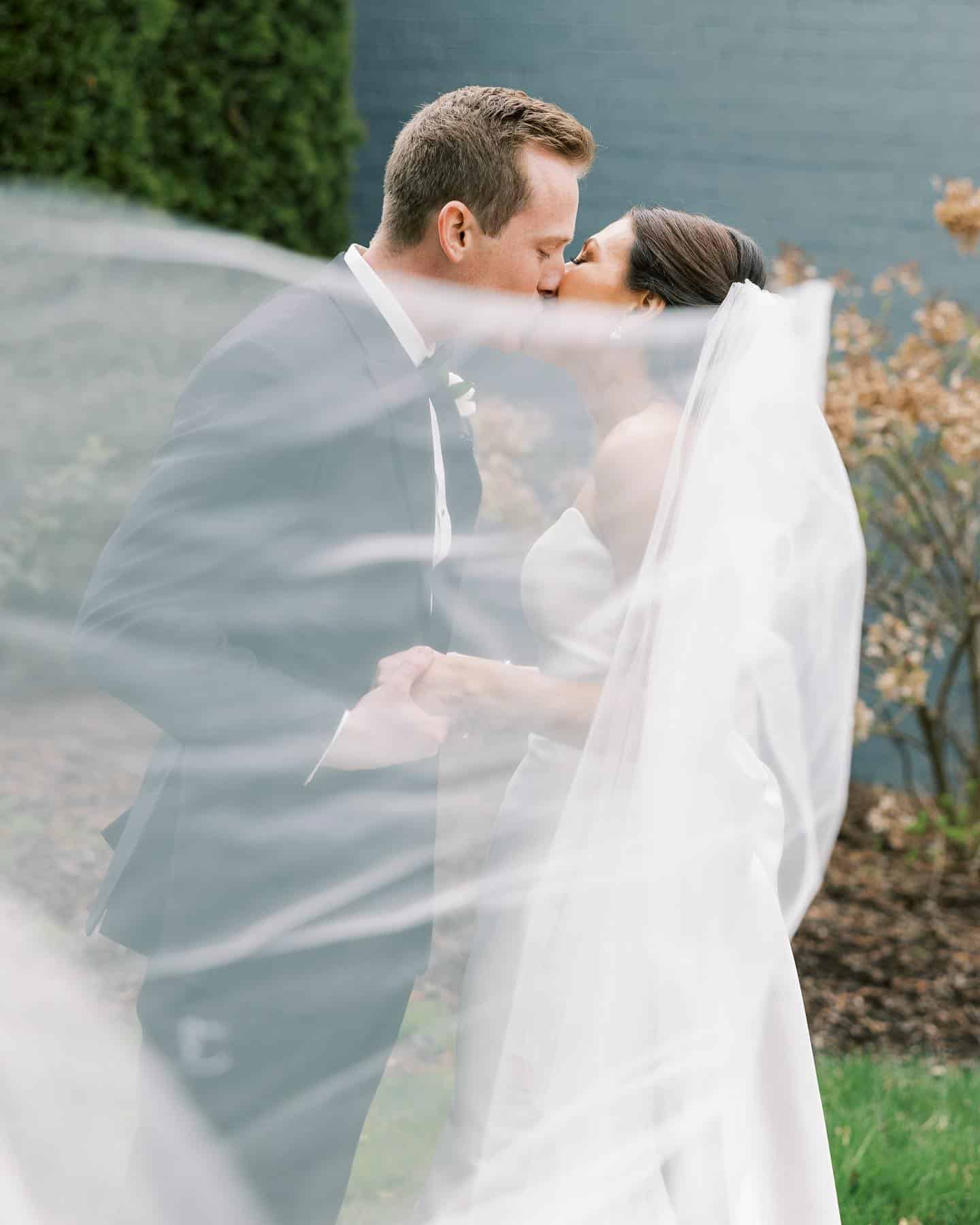 bride and groom kissing behind veil