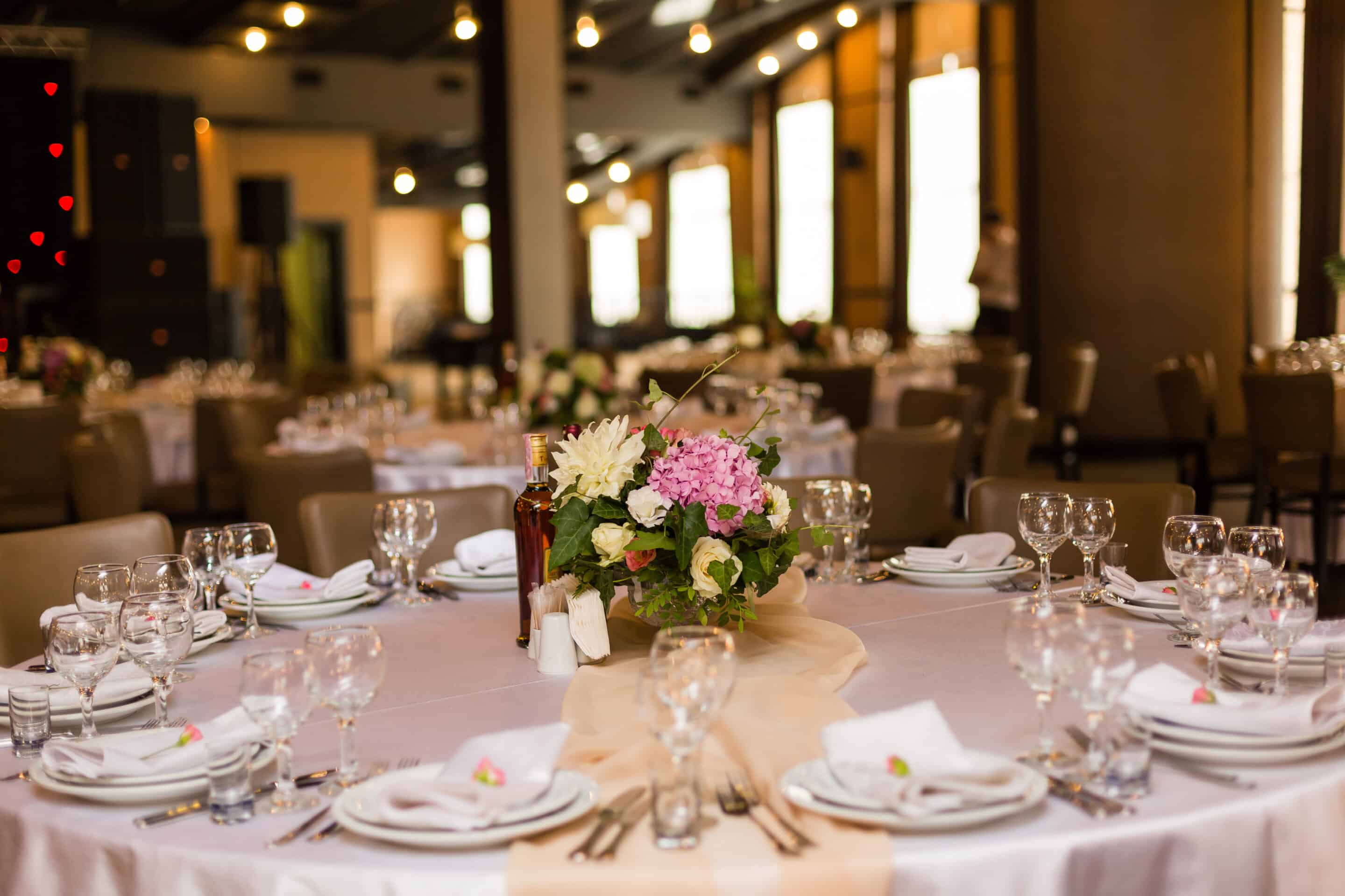 Elegant Michigan wedding venue ballroom at Crystal Gardens in Howell with crystal chandeliers and round tables set for reception.