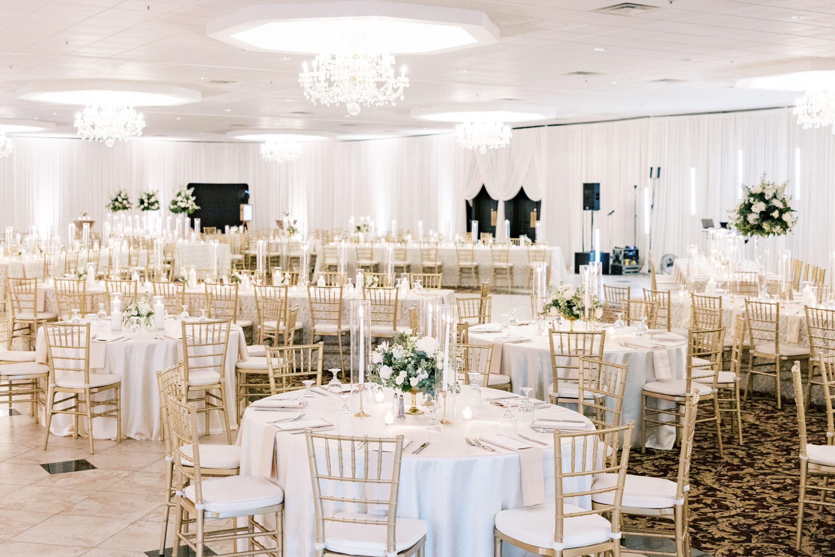 Elegant Michigan wedding venue ballroom at Crystal Gardens in Howell with crystal chandeliers and round tables set for reception.